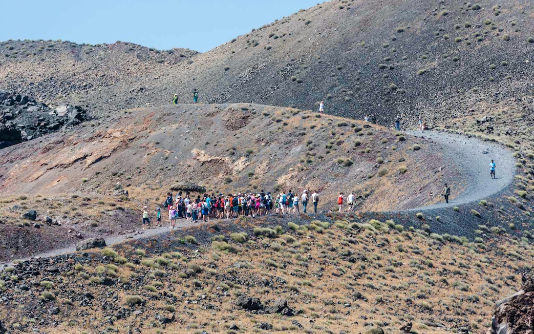 Guests hiking on volcanic terrain during Santorini Volcano Boat Tour.