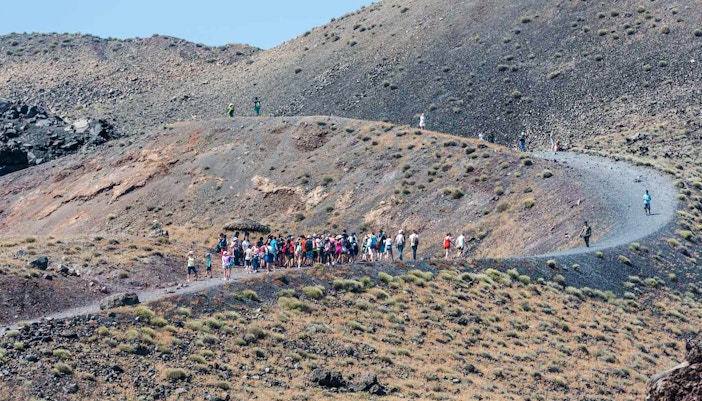 Guests hiking on volcanic terrain during Santorini Volcano Boat Tour.