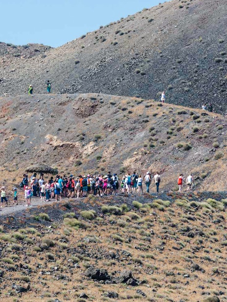 Guests hiking on volcanic terrain during Santorini Volcano Boat Tour.