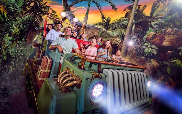 Visitors enjoying a thrilling ride at IMG World of Adventure, surrounded by jungle scenery.