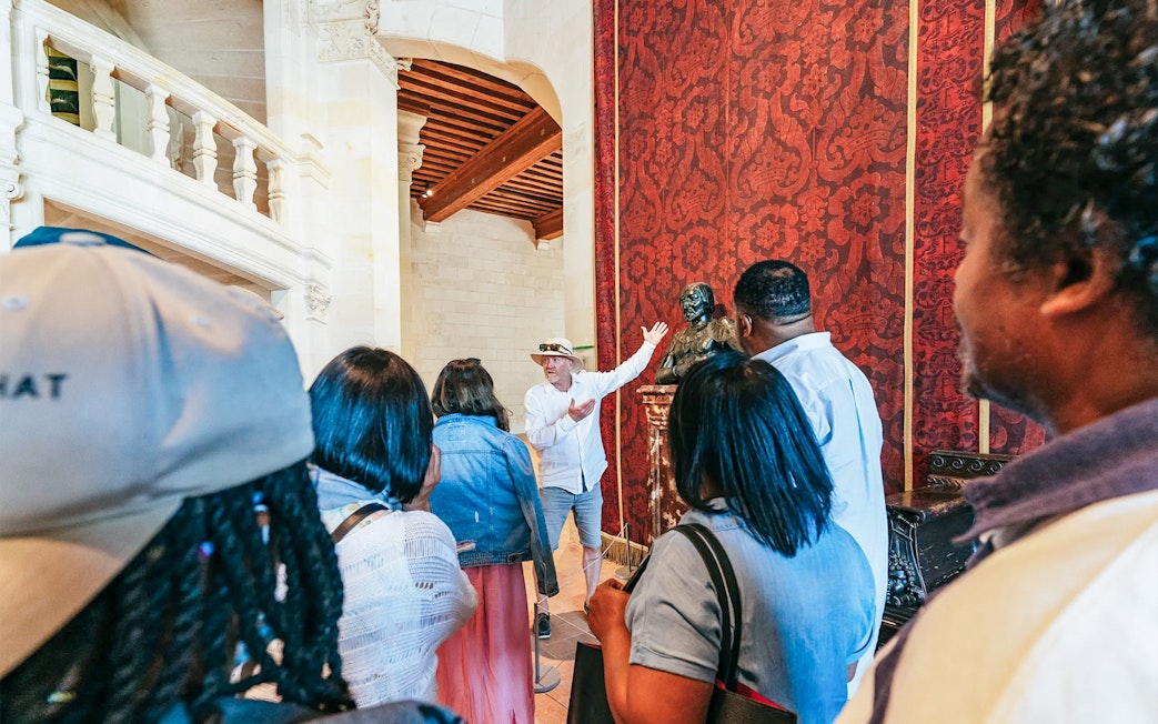 Guide explaining a statue to visitors inside Chambord Castle.