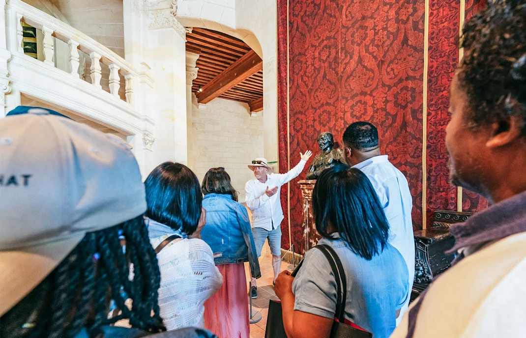 Visitors with a guide exploring the grand halls of Chambord Castle, Loire Valley, France.