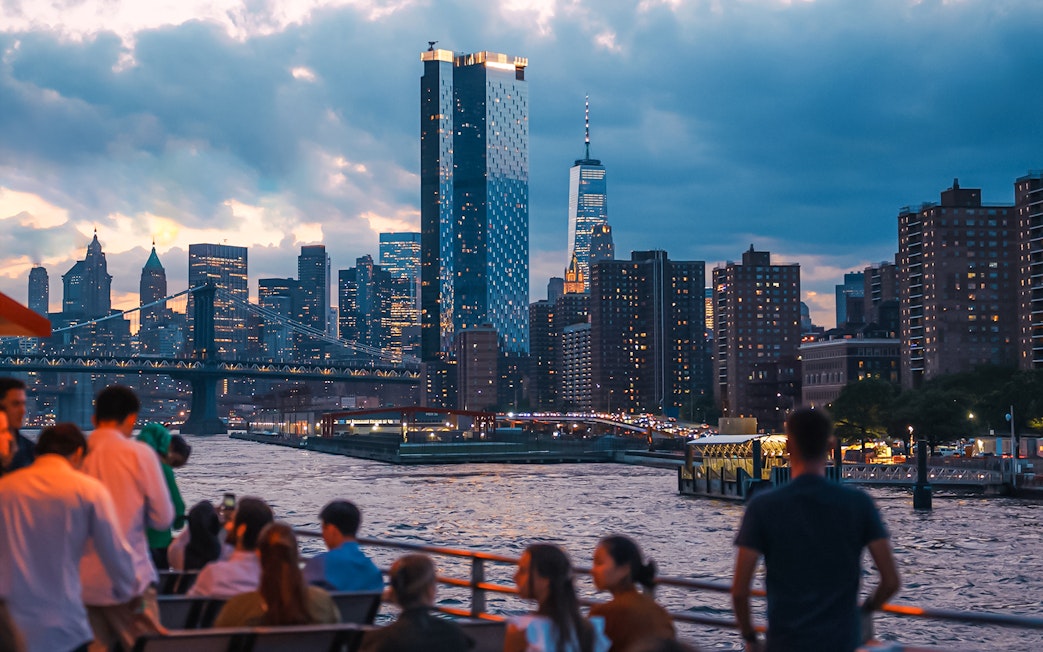 New York City skyline at night with people on a boat tour.