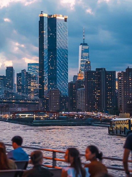 New York City skyline at night with people on a boat tour.