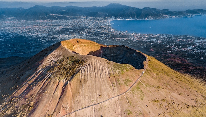 Hikers ascending Mount Vesuvius with panoramic views of the surrounding landscape.