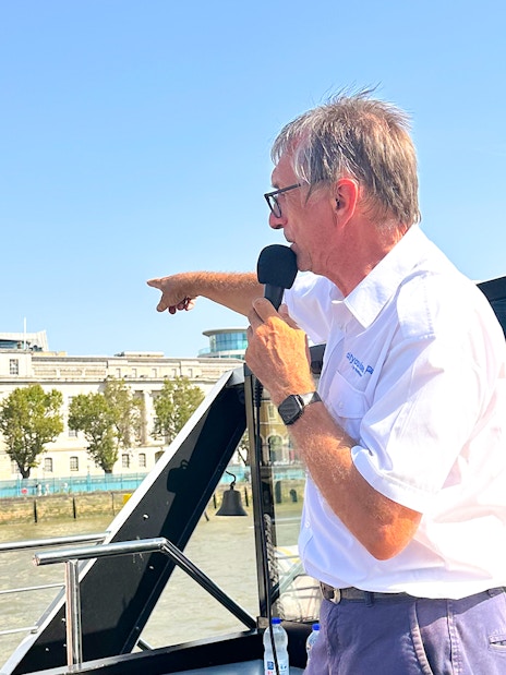 Tour guide speaking to tourists on a Seine River cruise in Paris.