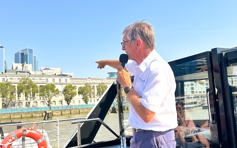 Tour guide speaking to tourists on a Seine River cruise in Paris.