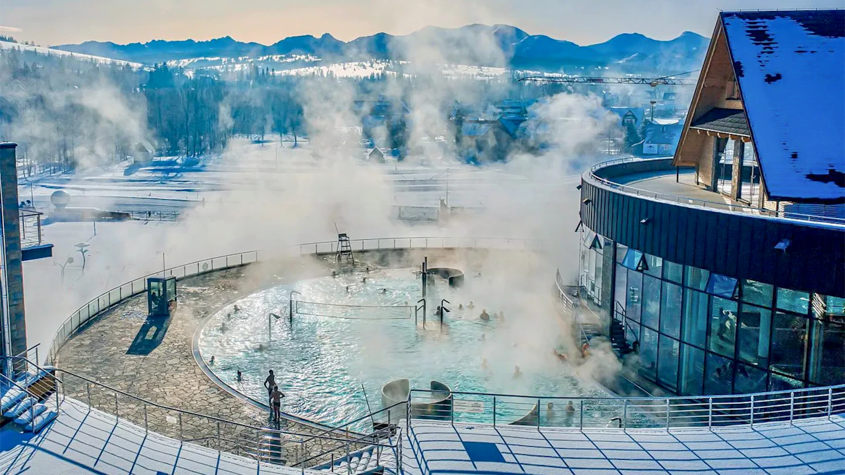 Thermal pools with steam rising, surrounded by snow, in Zakopane.