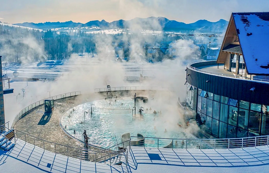 Thermal pools with steam rising, surrounded by snow, in Zakopane.
