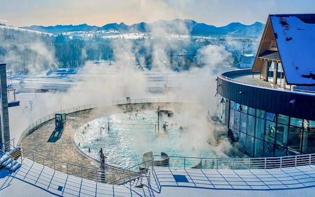 Thermal pools with steam rising, surrounded by snow, in Zakopane.