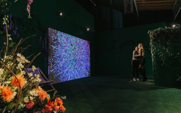 Visitors enjoying Monet's Garden immersive exhibition in Vienna with vibrant digital art display.