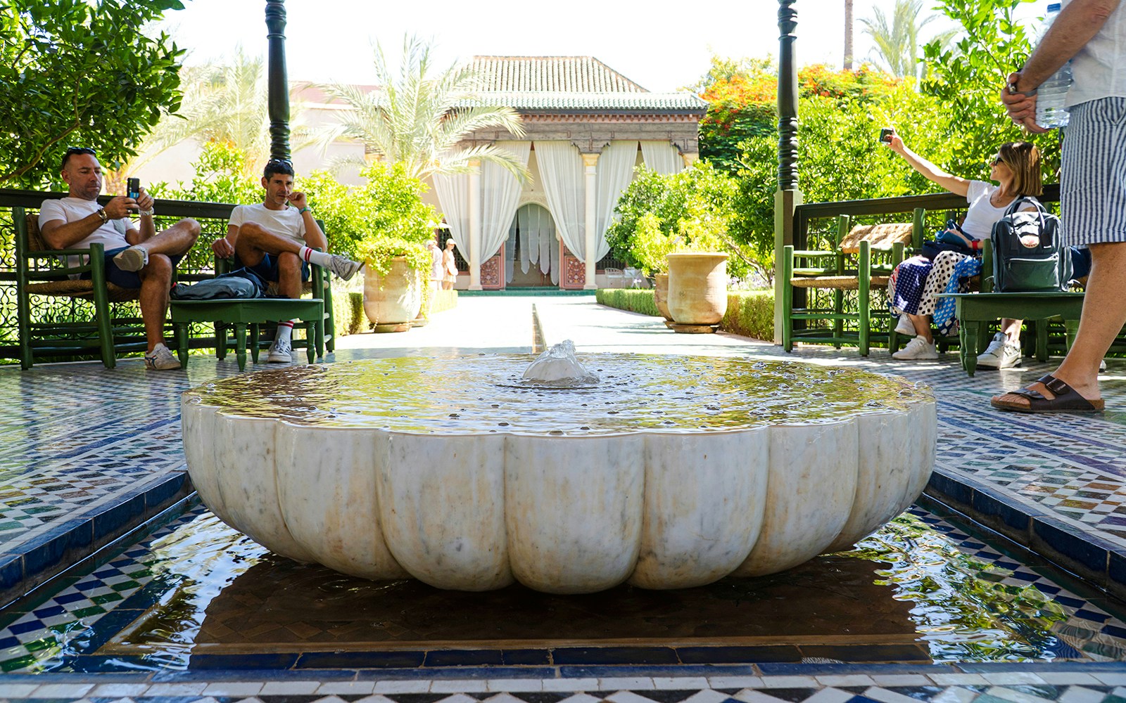Fountain in Jardin Secret courtyard with visitors relaxing on benches.