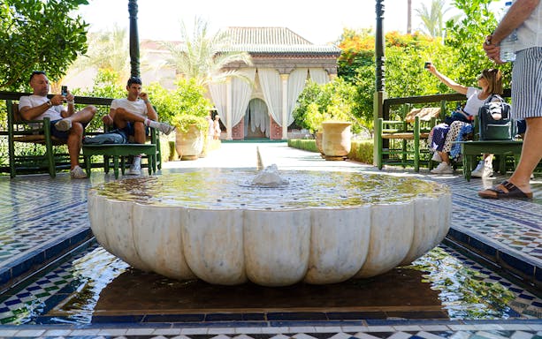 Fountain in Jardin Secret courtyard with visitors relaxing on benches.