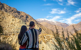 Tourists at Salto del Soldado viewpoint in Chile, admiring mountain landscape.