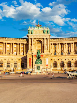 Austrian National Library at Hofburg Complex, Vienna, with equestrian statue and visitors.
