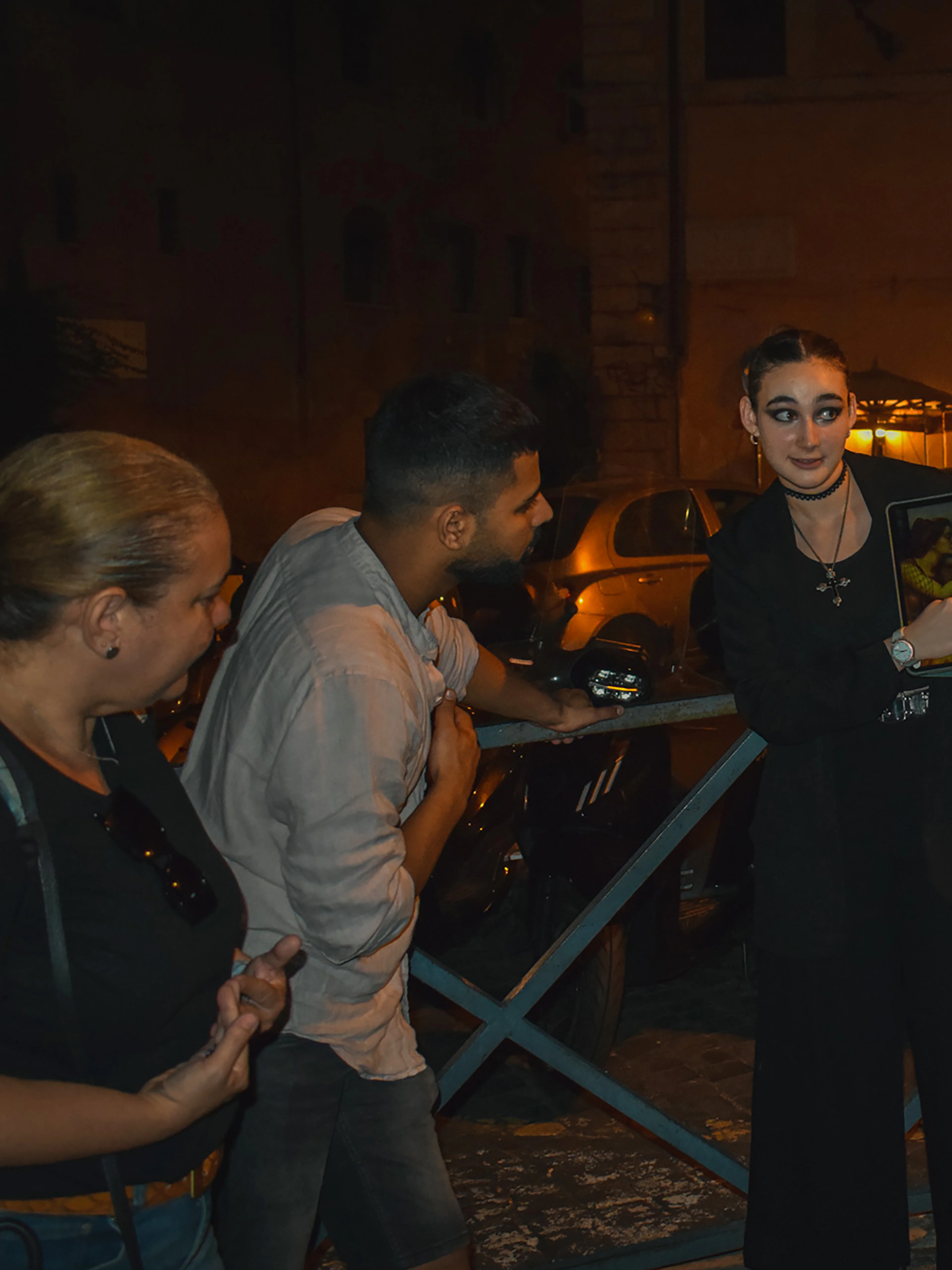 Tour guide showing a tablet to a group during a ghost walking tour in Rome at night.