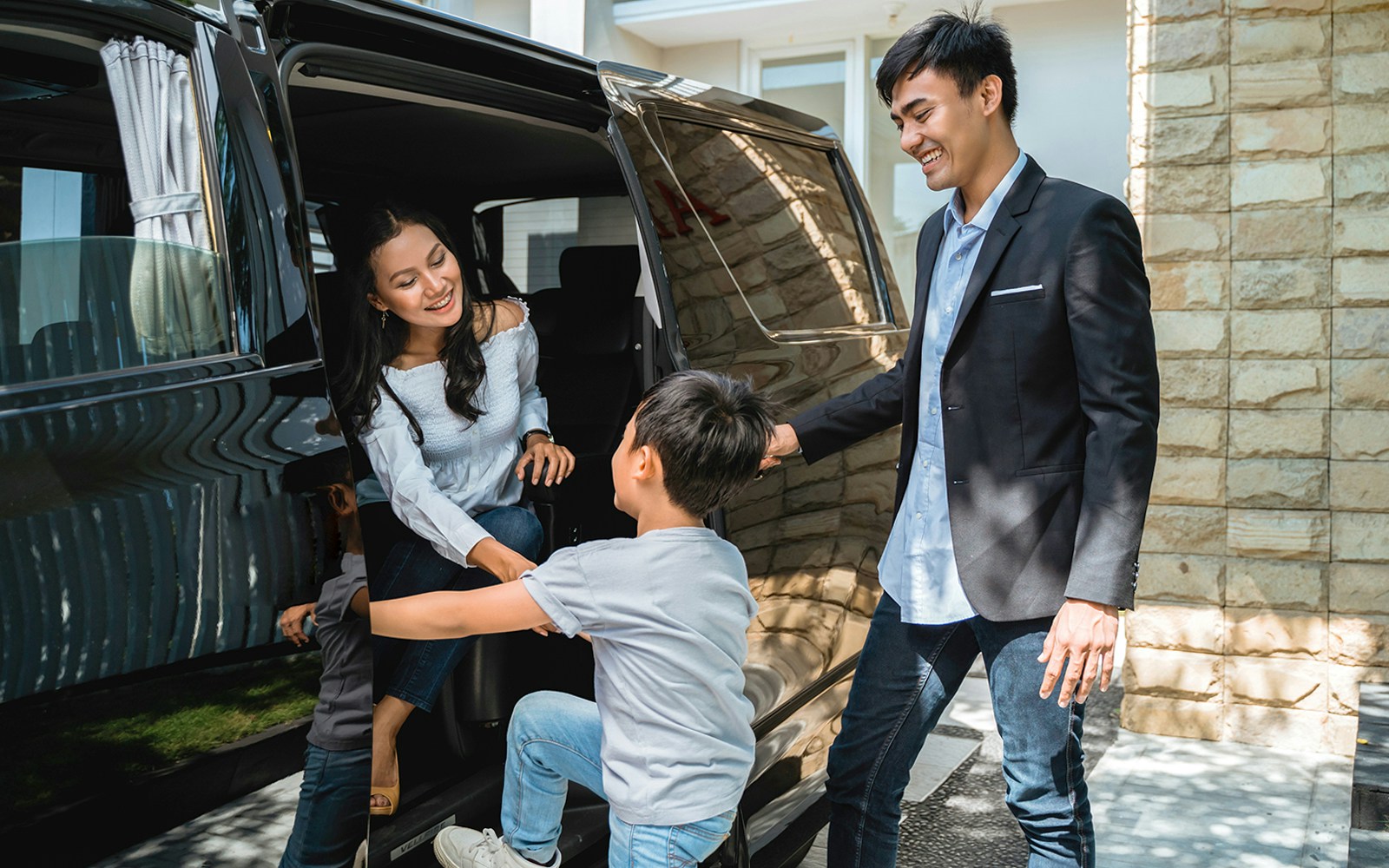 Couple entering vehicle for roundtrip transfer with child assisting.