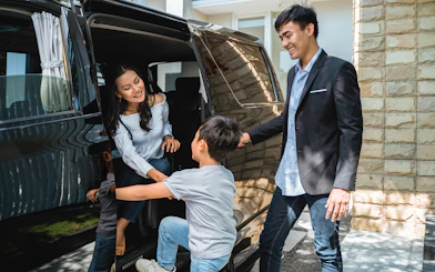 Couple entering vehicle for roundtrip transfer with child assisting.