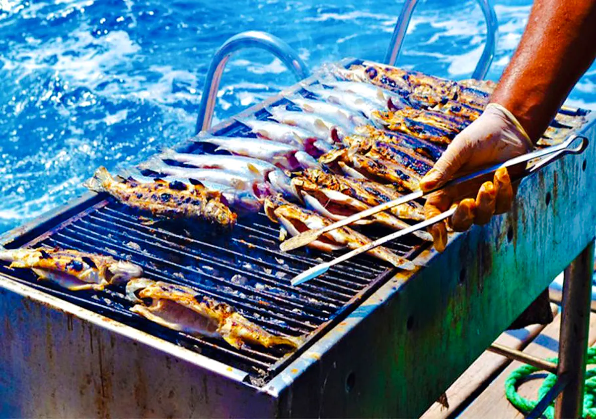 Grilling fish on a boat during a half-day trip from Agadir, Morocco.