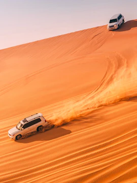 SUVs driving on sand dunes in Abu Dhabi desert.
