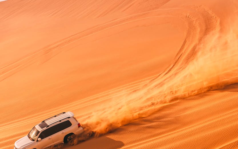SUVs driving on sand dunes in Abu Dhabi desert.