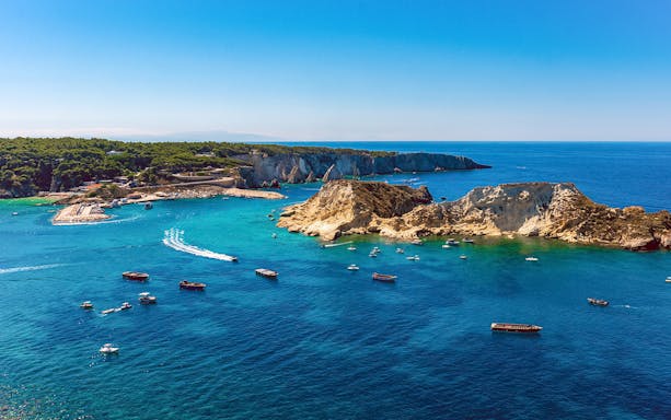 Ferry boats on turquoise waters near rocky coastline of Tremiti Islands, Italy.