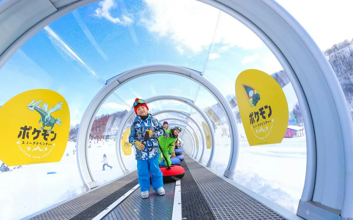 Children on a conveyor belt at Kashimayari Ski Resort, Nagano, with snowy landscape.
