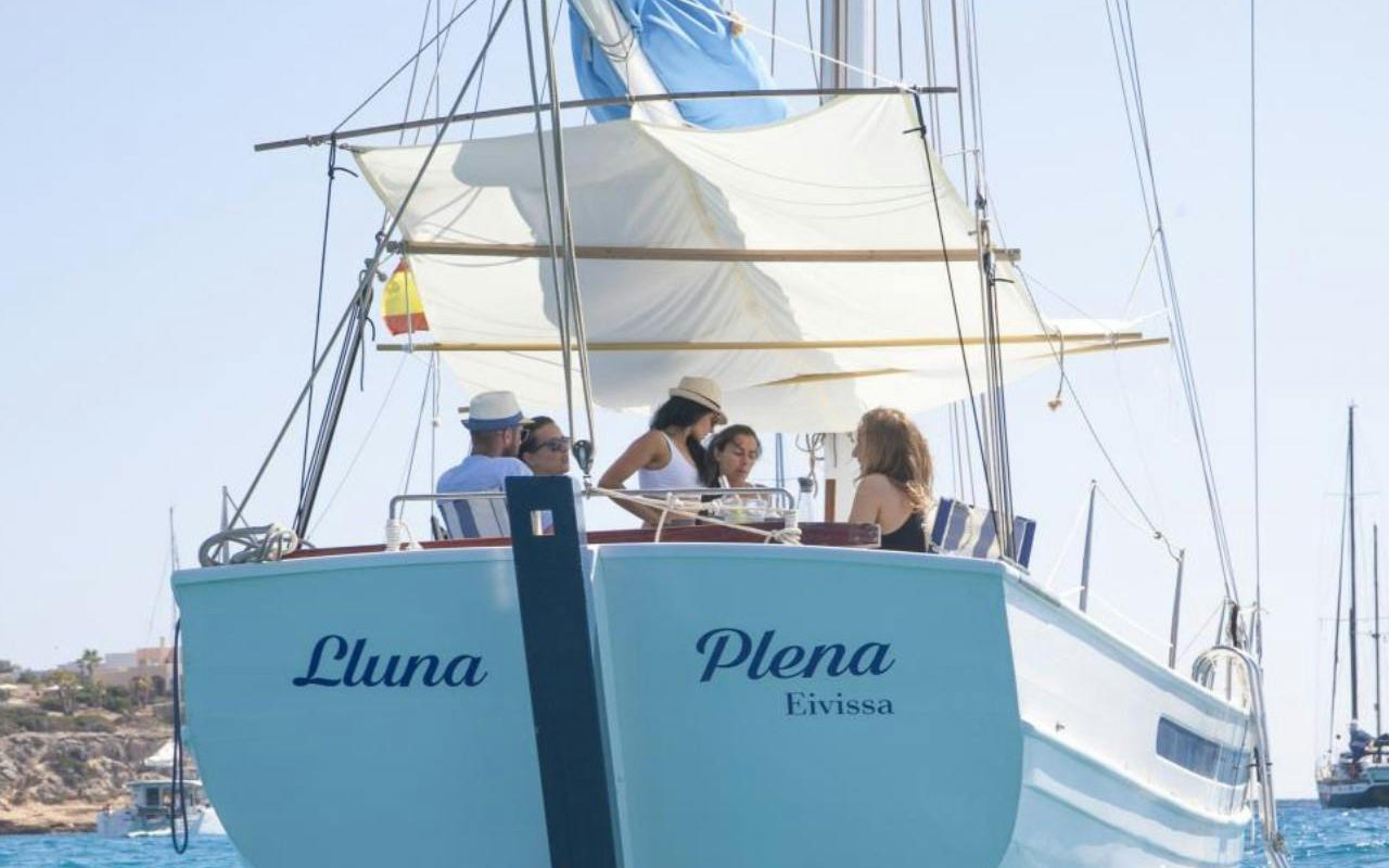 Tourists enjoying a private sunset cruise on a classic boat in Ibiza.