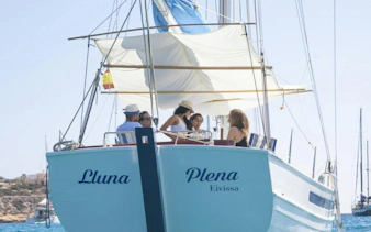 Tourists enjoying a private sunset cruise on a classic boat in Ibiza.