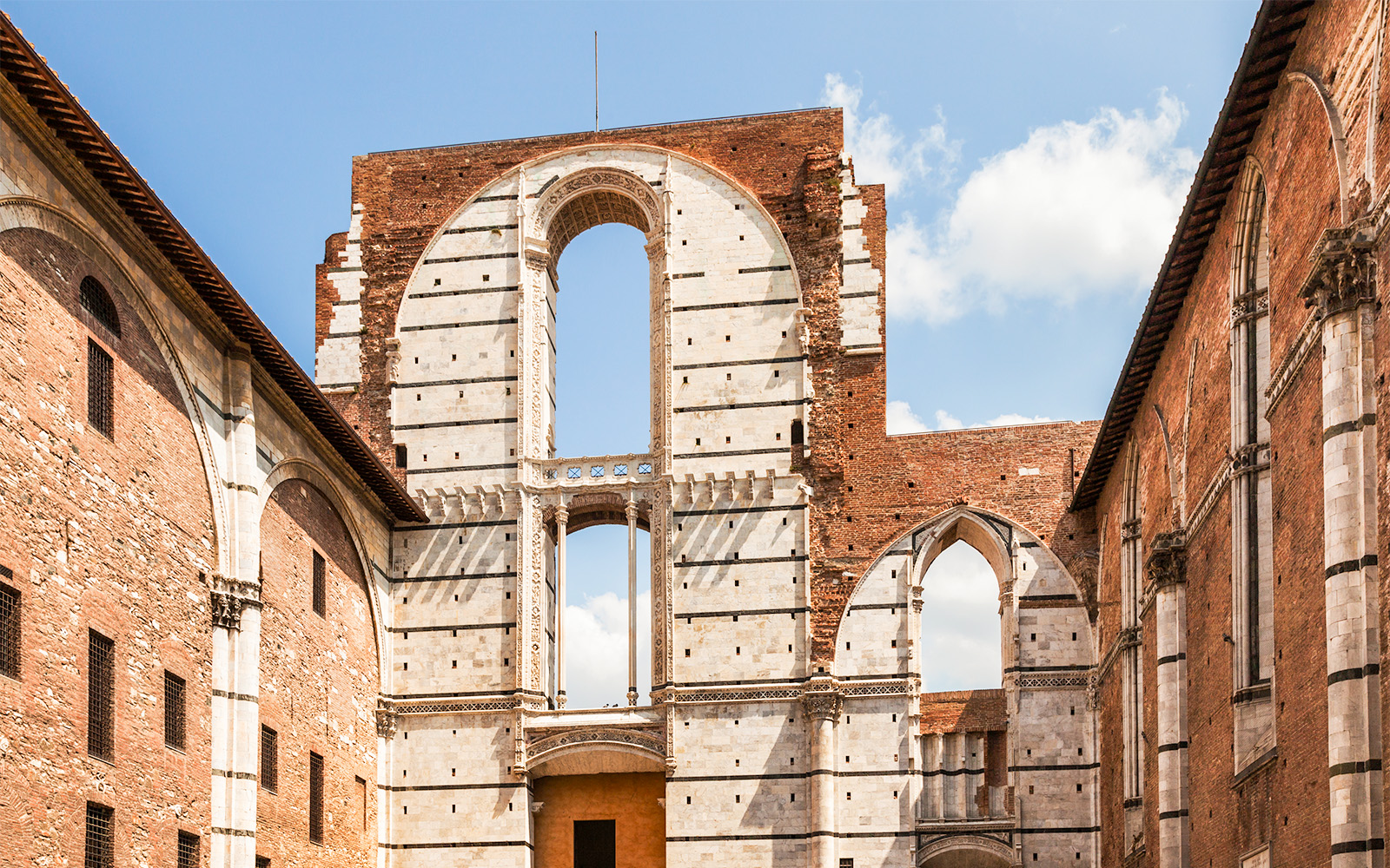 Siena Cathedral Complex facade with arches and brick walls, Italy.