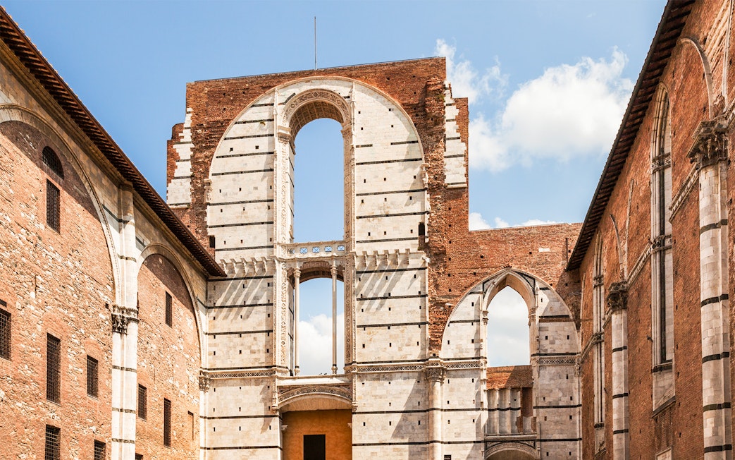 Siena Cathedral Complex facade with arches and brick walls, Italy.