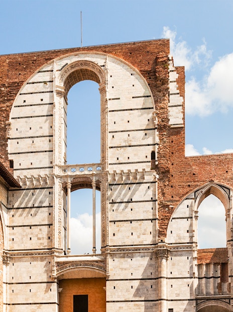 Siena Cathedral Complex facade with arches and brick walls, Italy.