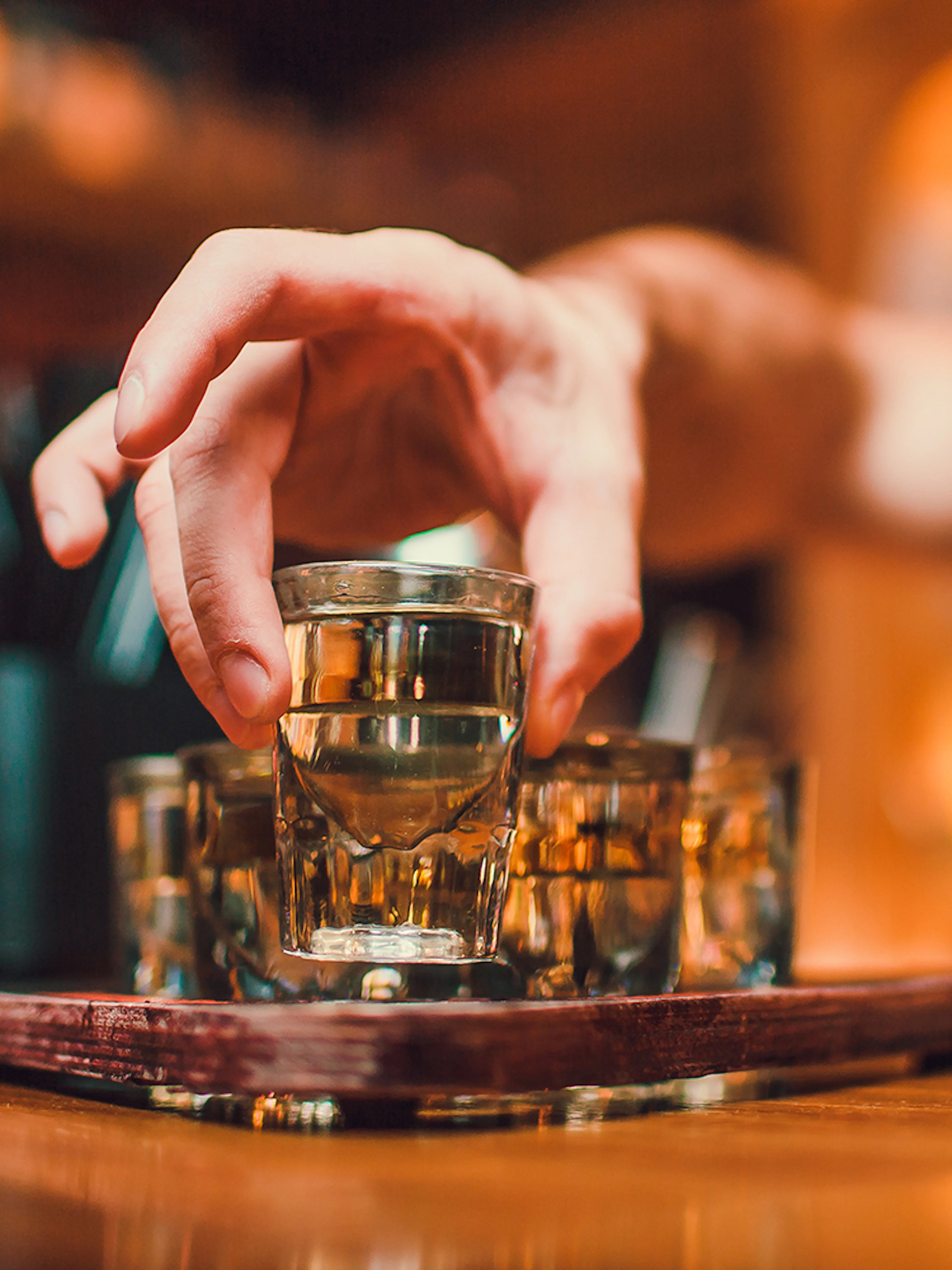 Hand reaching for a vodka shot glass during a tasting session in Wroclaw.