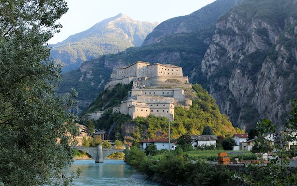 Fortress of Bard on a hill with surrounding mountains and river, Italy.