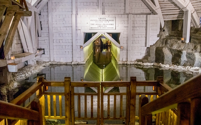 Wieliczka Salt Mine underground lake with wooden railing and illuminated grotto entrance.