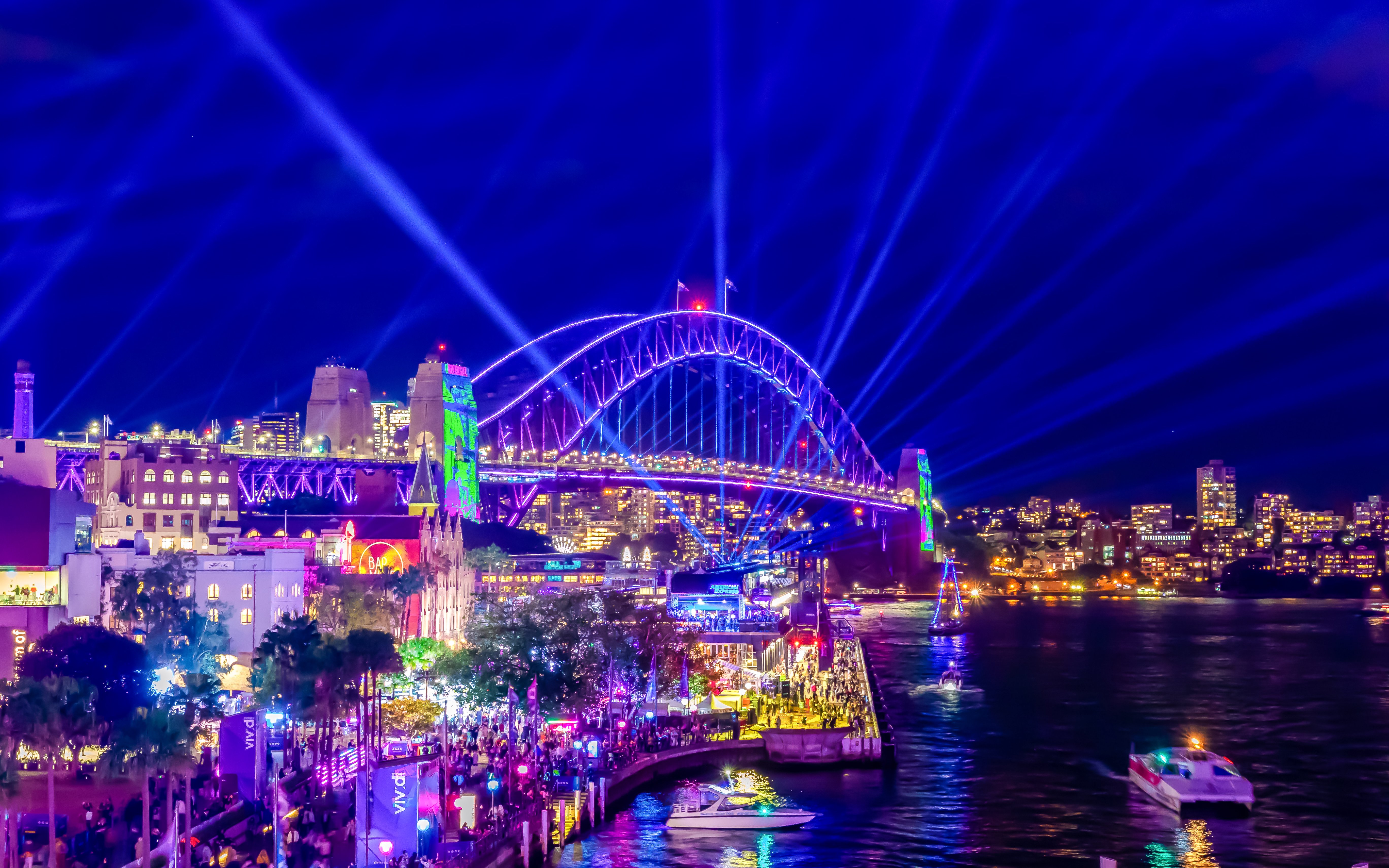 Sydney Harbour Bridge illuminated during a vibrant light show at night.
