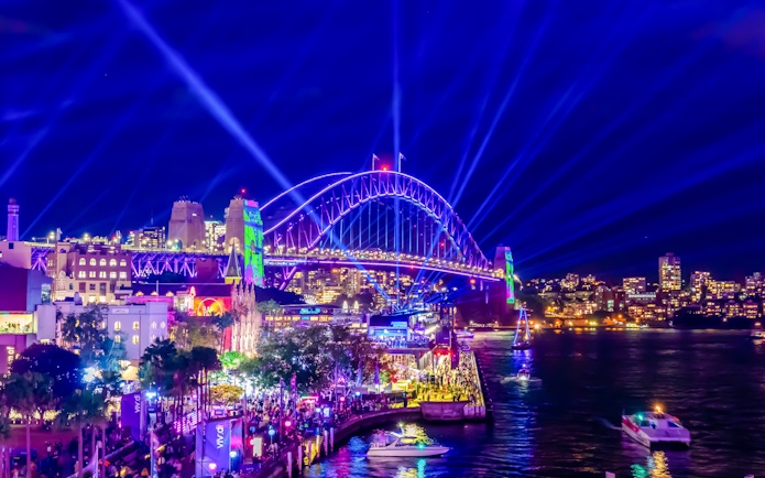Sydney Harbour Bridge illuminated during a vibrant light show at night.