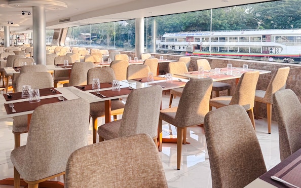 Dining area on The Luxury White Cruise ship with tables set for guests.