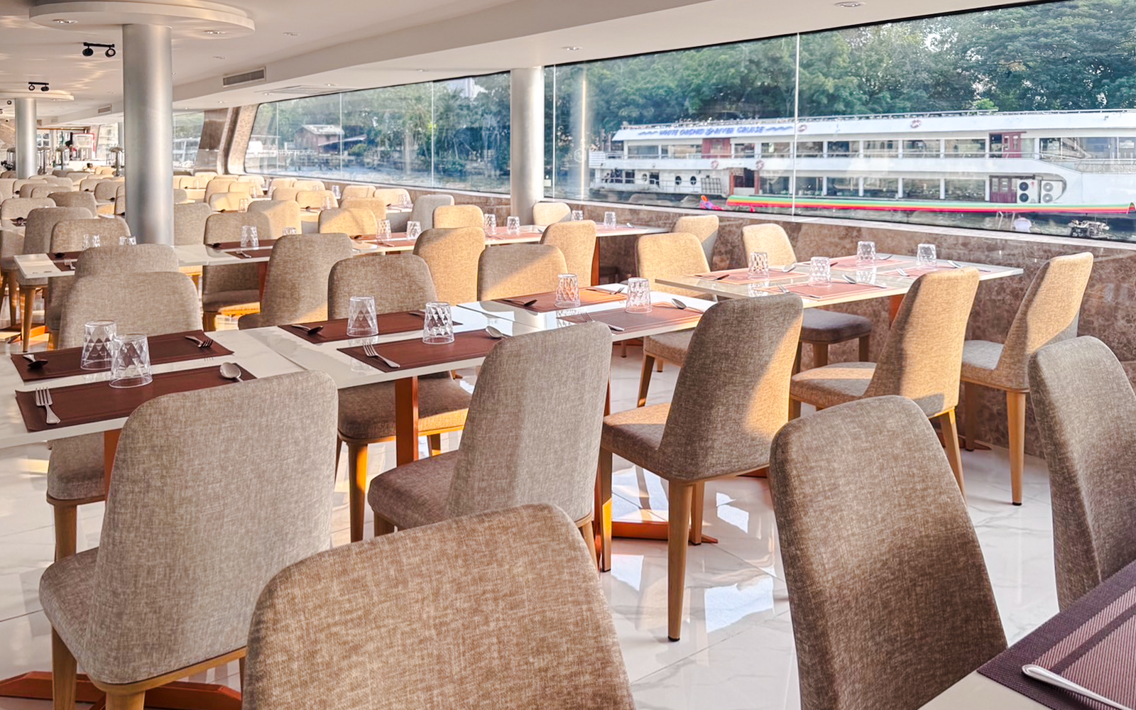 Luxury White Cruise ship interior with elegant dining area and panoramic windows, offering scenic ocean views.