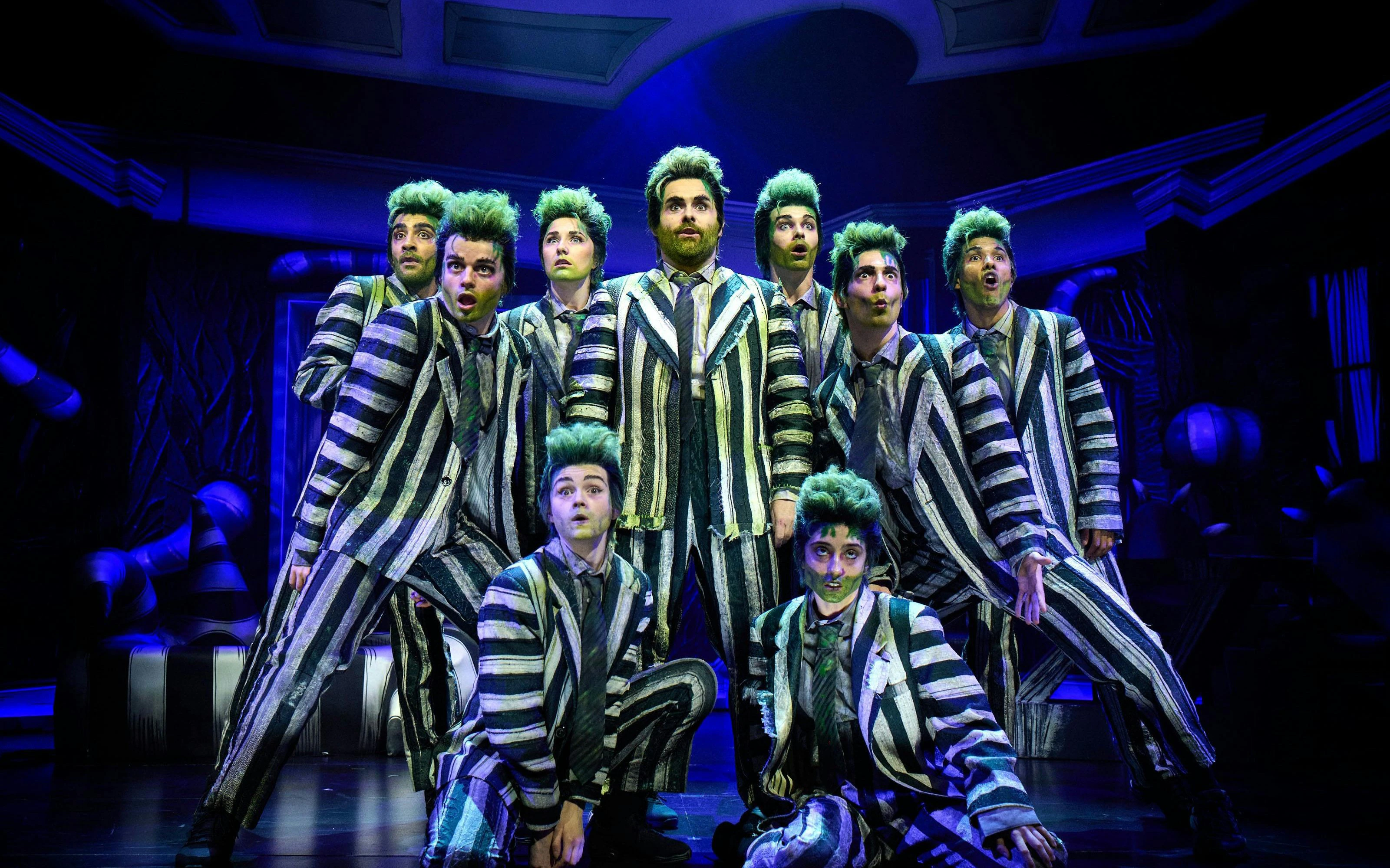 Beetlejuice cast performing on West End stage in striped costumes.