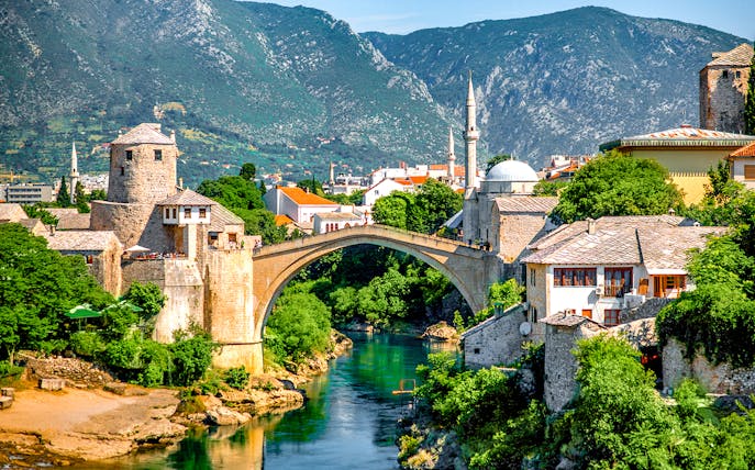 Stari Most bridge over Neretva River in Mostar, Bosnia and Herzegovina, with surrounding historic buildings.