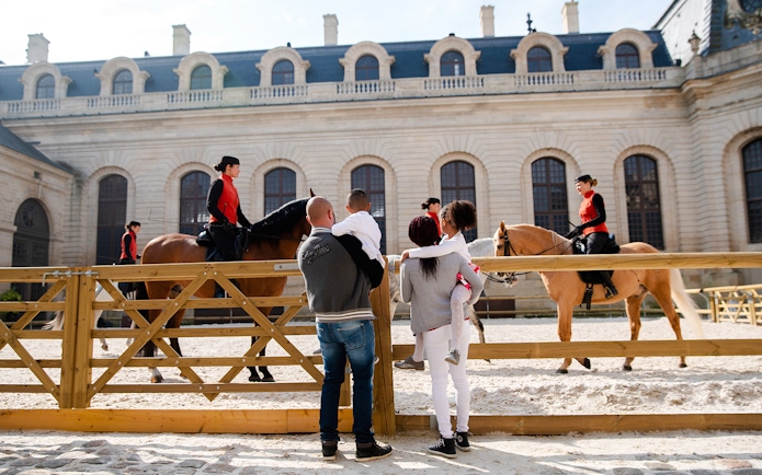 Family watching equestrian show at Chateau of Chantilly.