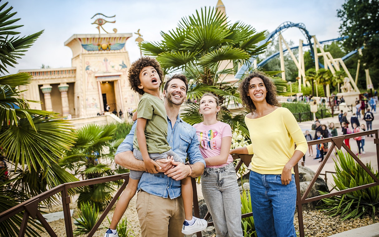 Family enjoying a day at Parc Asterix with Egyptian-themed attractions in the background.