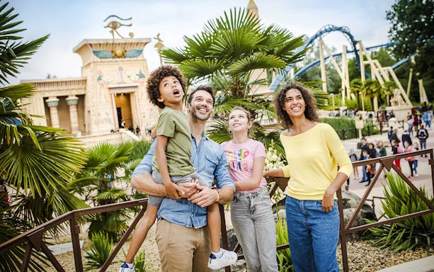 Family enjoying a day at Parc Asterix with Egyptian-themed attractions in the background.