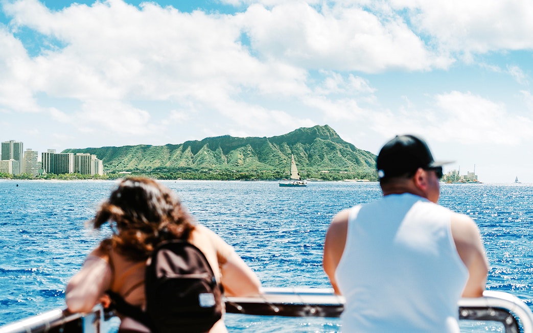 Glass-bottom boat view of Diamond Head, Oahu, Hawaii, with tourists observing the coastline.