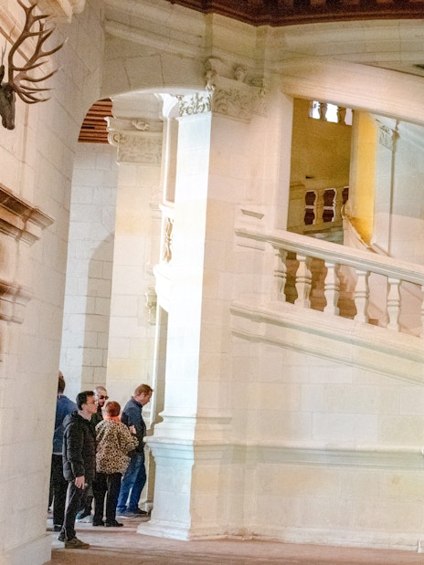 Chambord Castle's double helix staircase with visitors exploring.