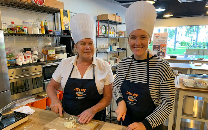 Culinary tour participants chopping ingredients in a kitchen during a Market to Table experience.