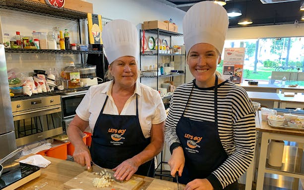 Culinary tour participants chopping ingredients in a kitchen during a Market to Table experience.