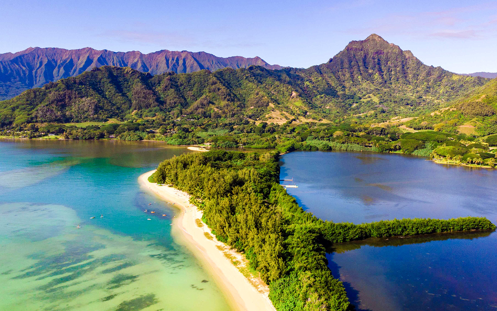 Aerial view of Secret Island and Moli'i Pond in Hawaii with lush greenery and surrounding mountains.