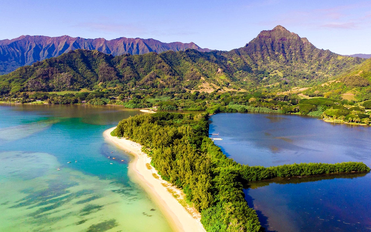 Aerial view of Secret Island and Moli'i Pond in Hawaii with lush greenery and surrounding mountains.